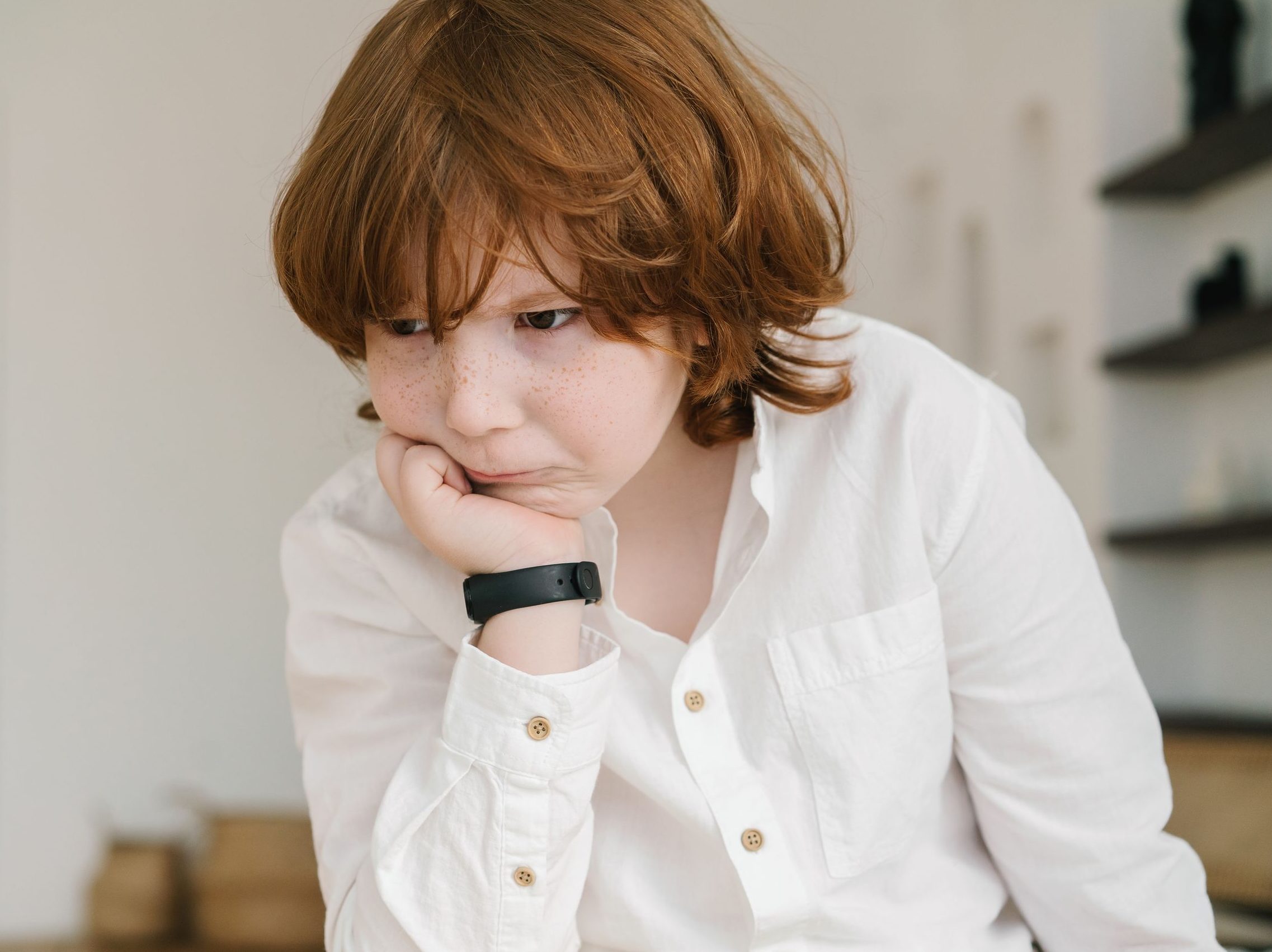 A young boy with freckles in deep concentration, wearing a white shirt.