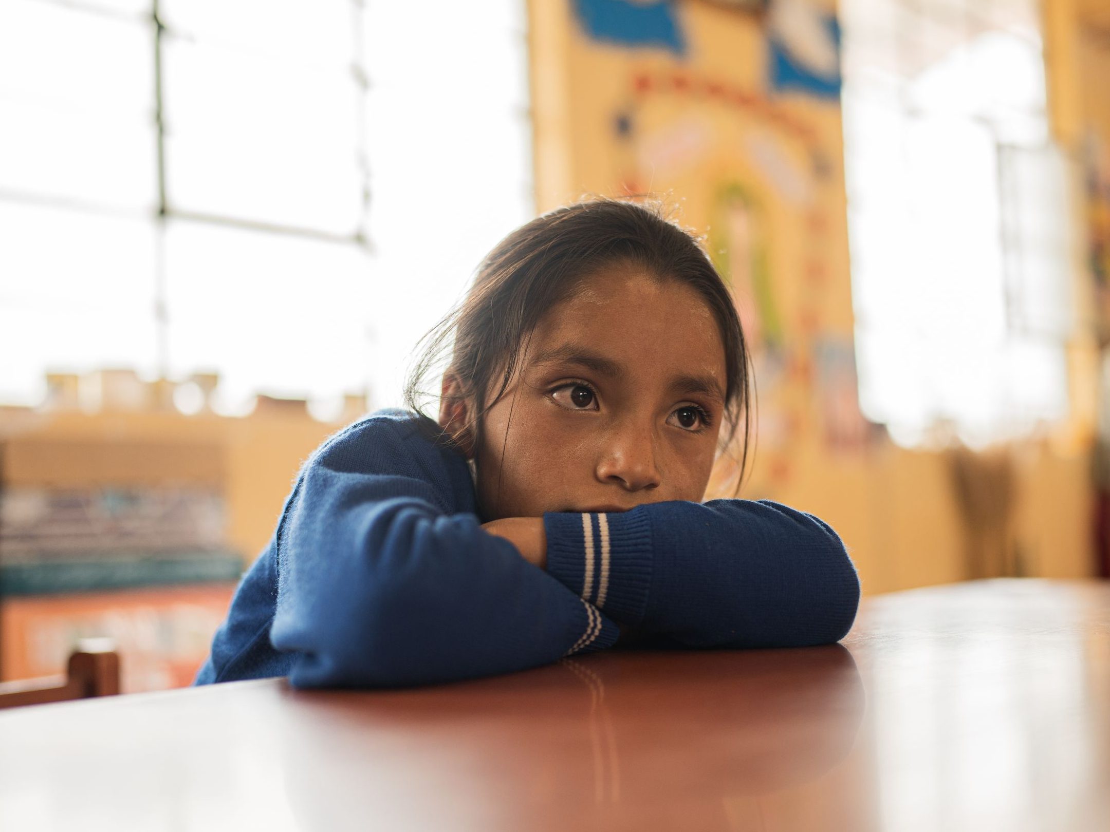 A young girl in a school classroom in Yungay, Perรบ, appears thoughtful and introspective.