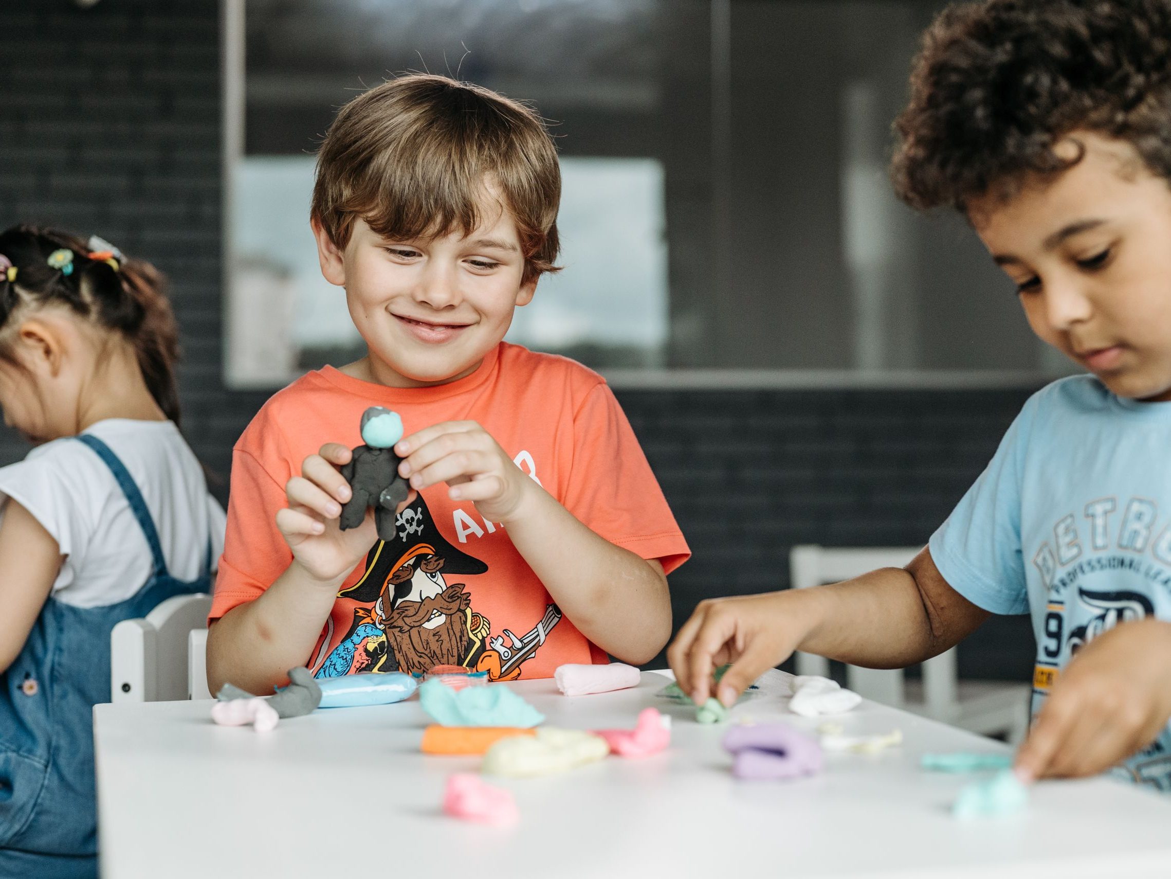 Children engaged in creative play with colorful clay indoors, expressing joy and imagination.