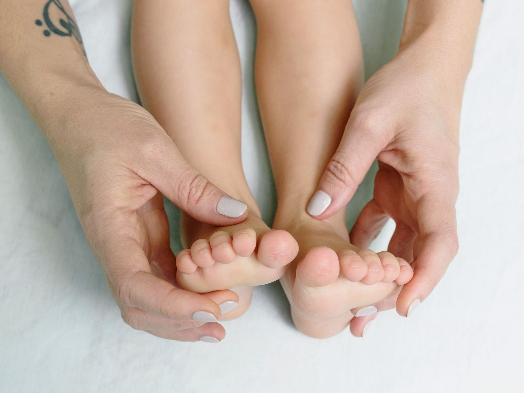 Close-up of a parent holding their child's feet for a gentle massage. Warm and loving scene.
