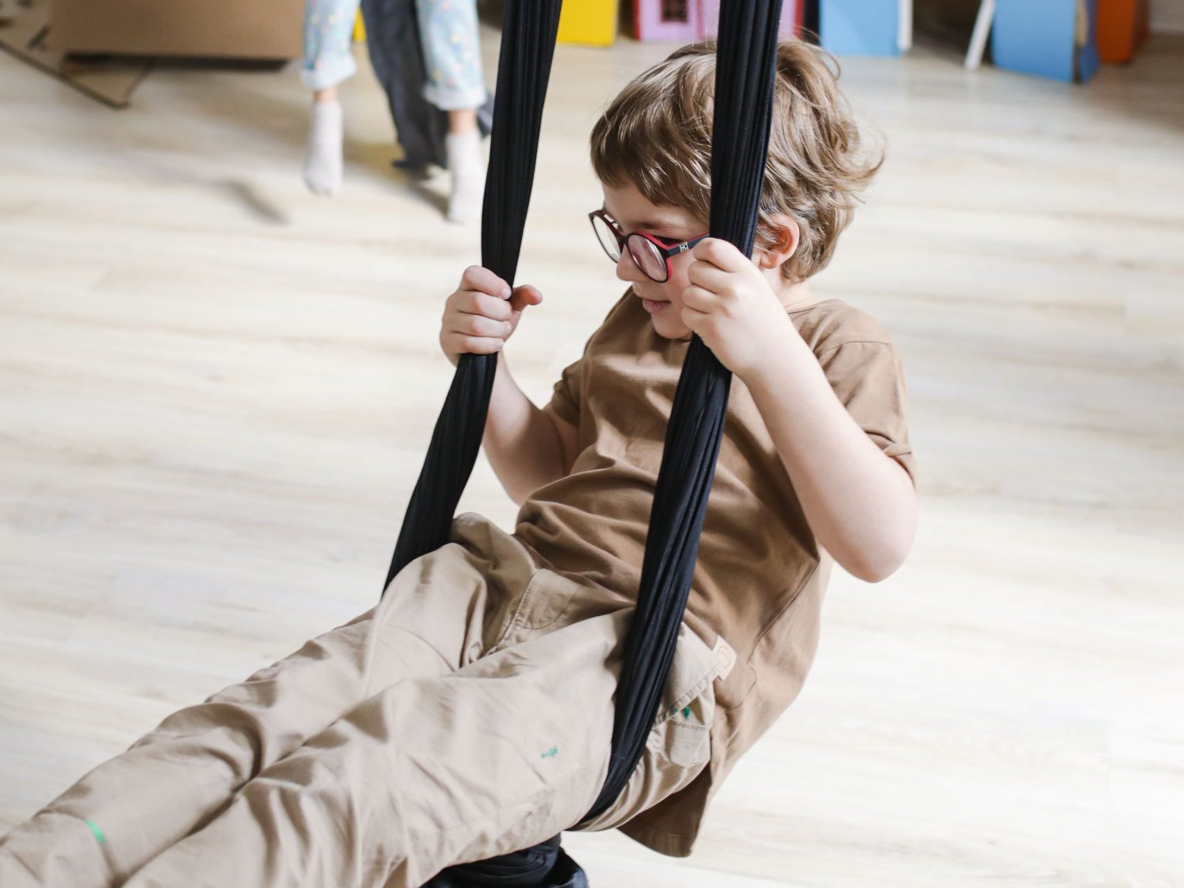 Joyful children enjoying playtime on swings in a colorful indoor playroom.