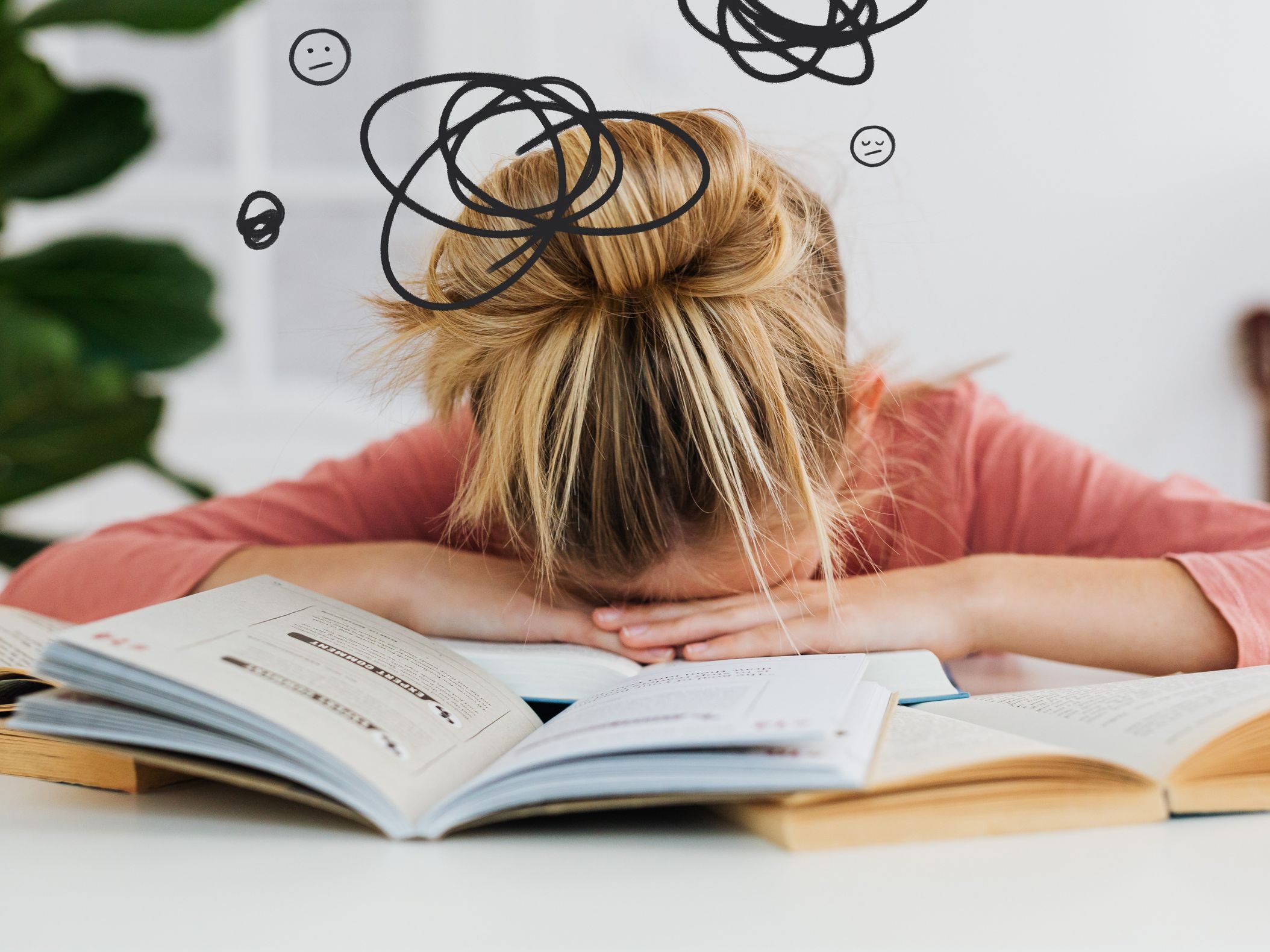 Young woman asleep over books at desk, conveying stress and mental overload.