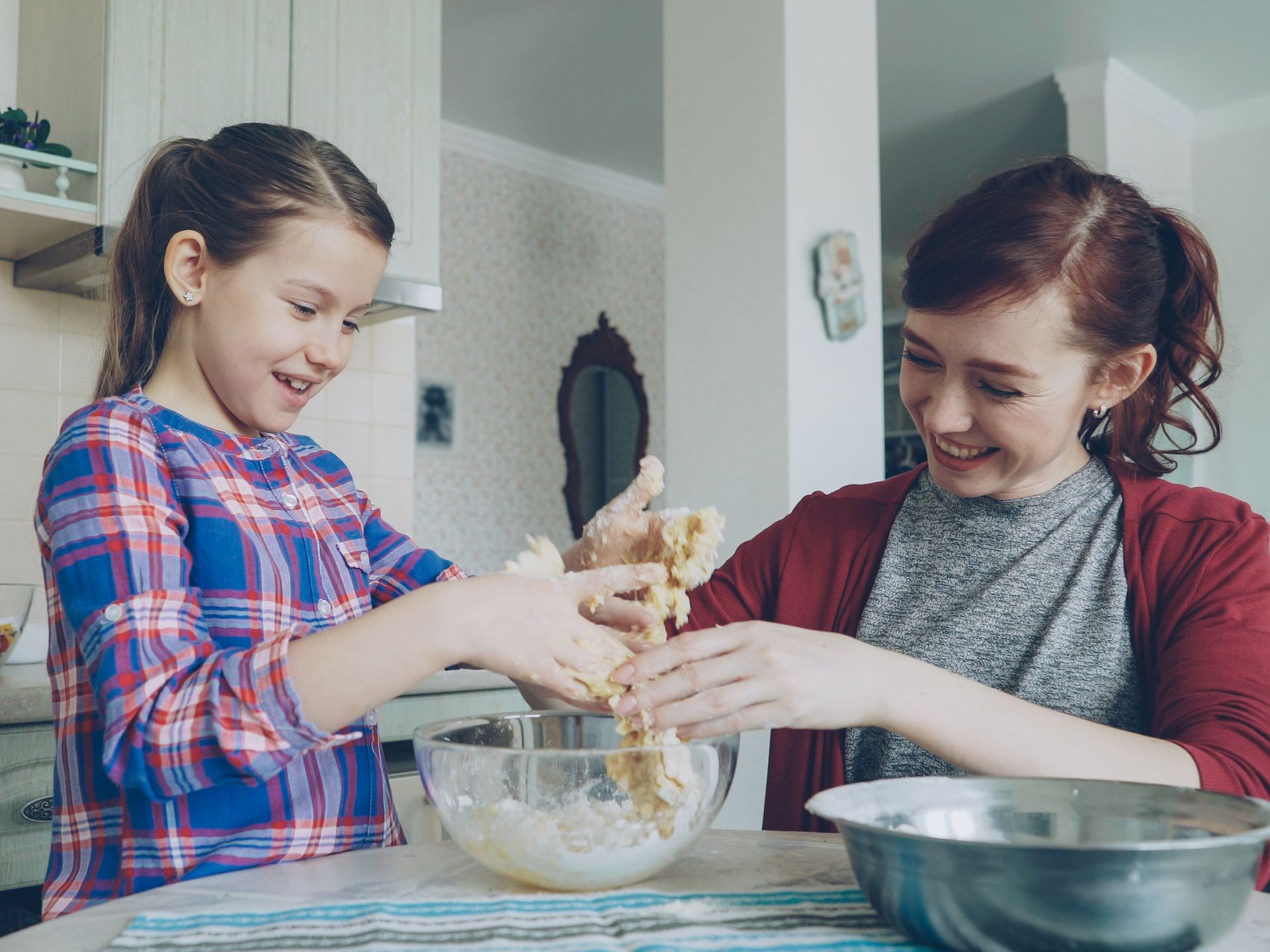 A mother and daughter enjoying baking together, mixing dough in the kitchen.