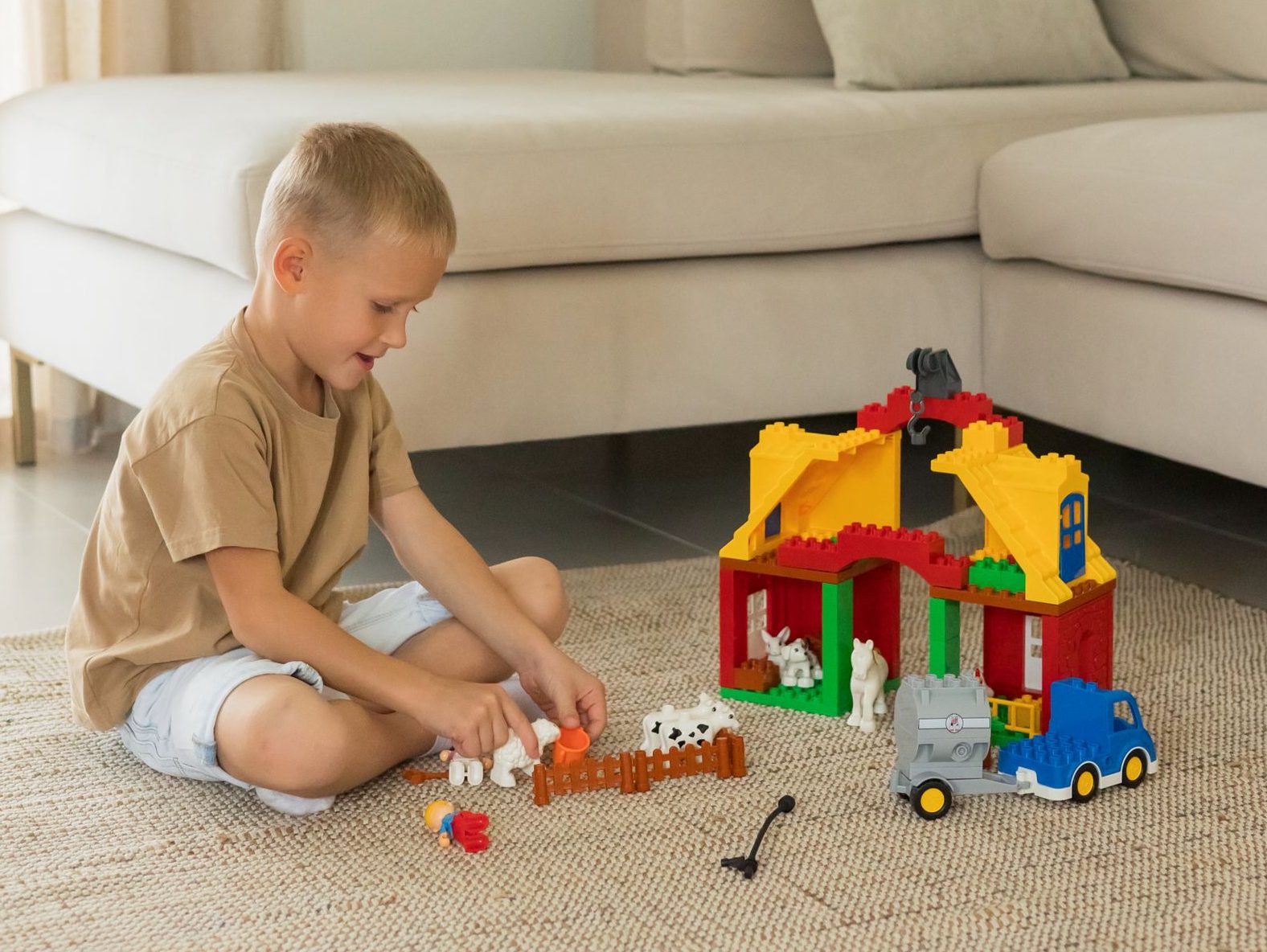 A young boy plays with colorful toy building blocks in a cozy living room setting, promoting creativity.