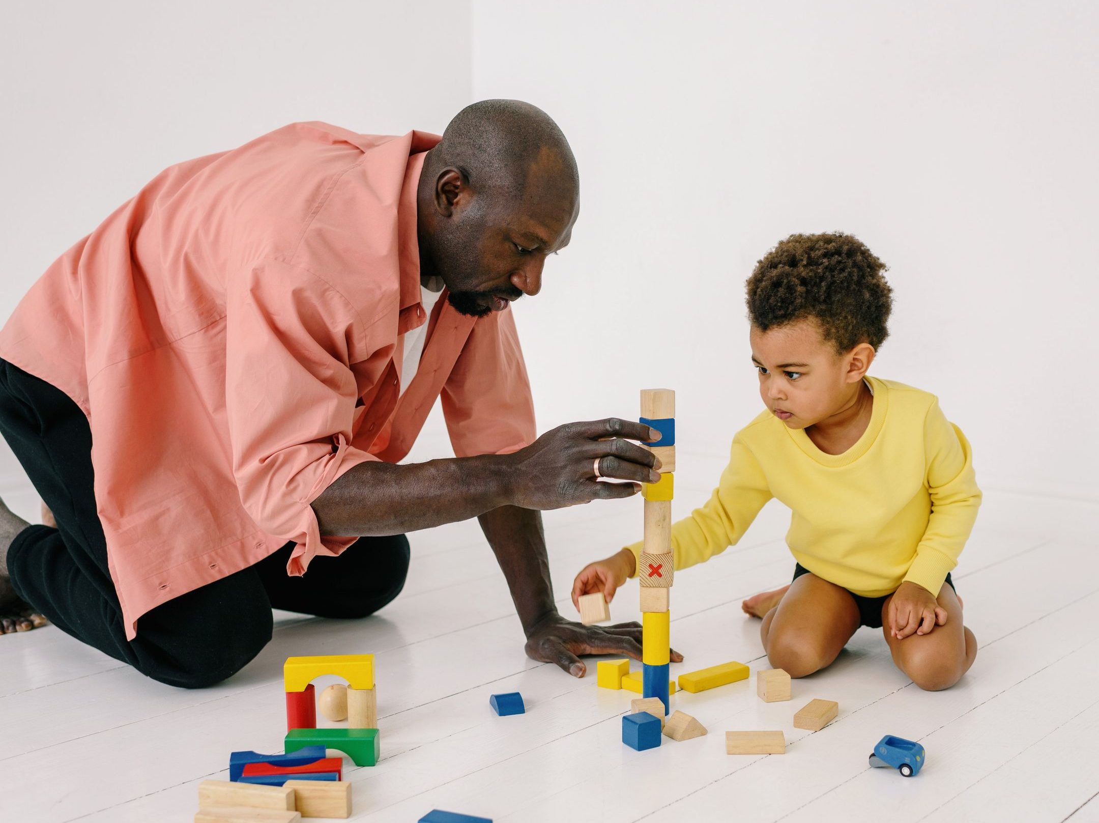 Father and son playing with wooden blocks indoors, enjoying quality family time together.